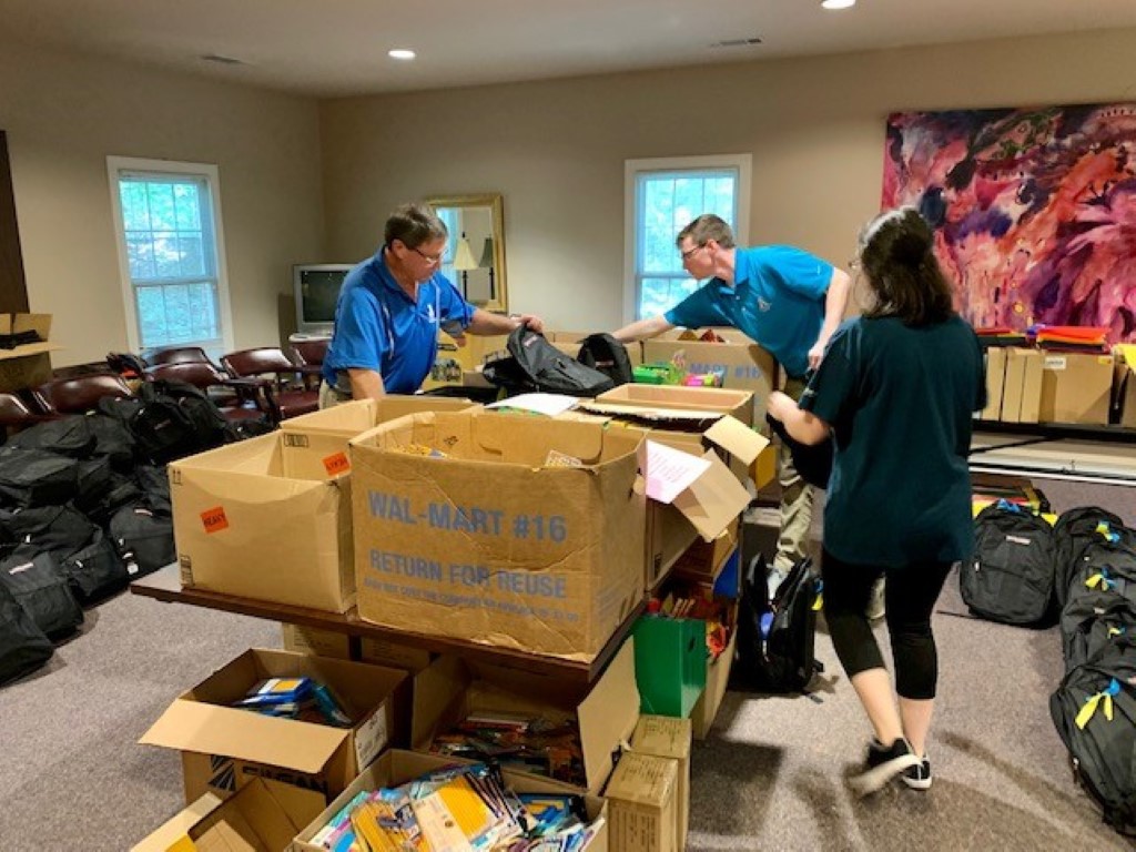 Volunteers sorting donations and packing backpacks