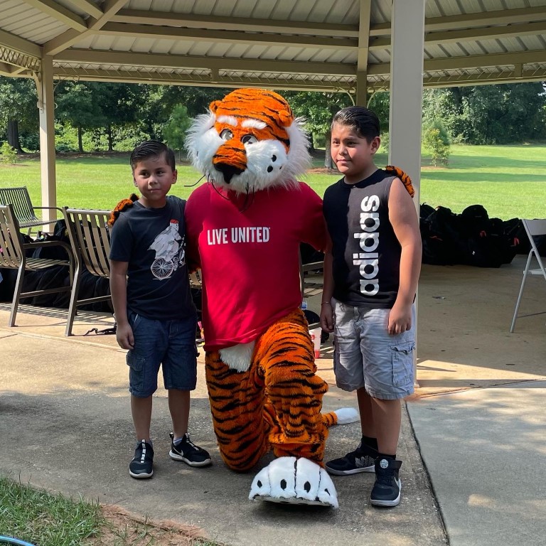 Aubie posing with a boy and girl