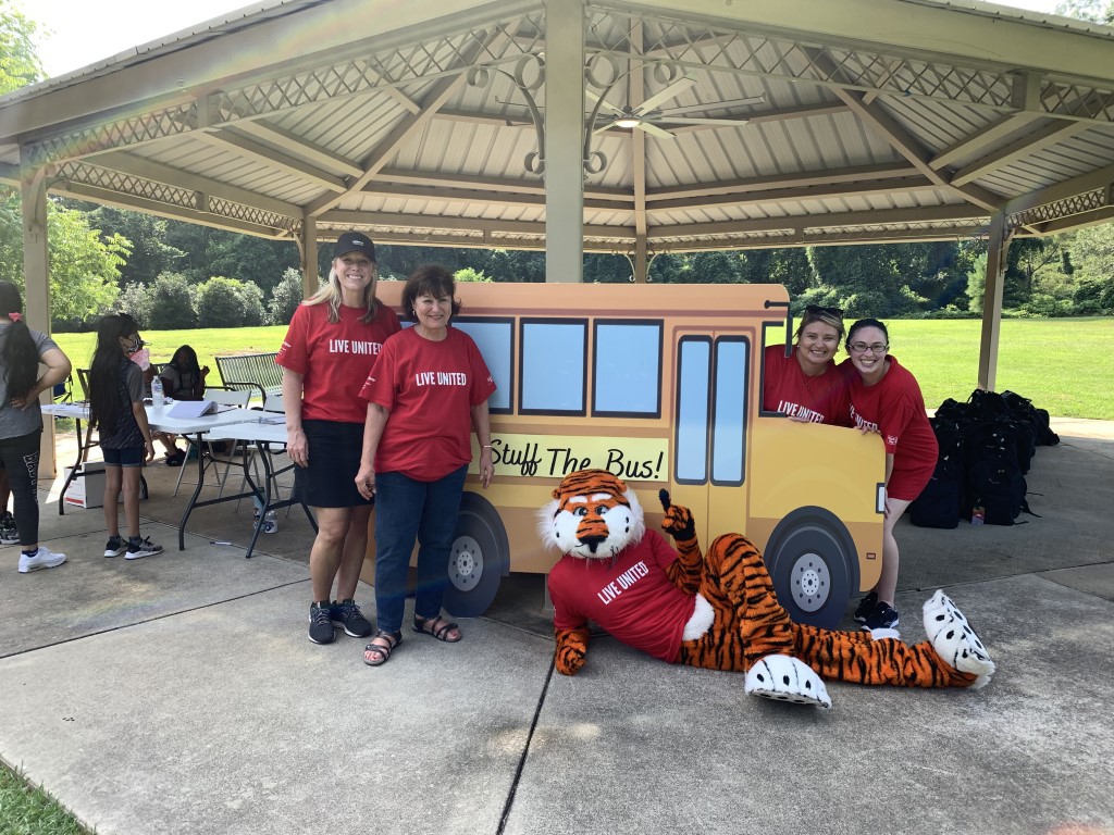 Aubie and volunteers posing in front of school bus cutout