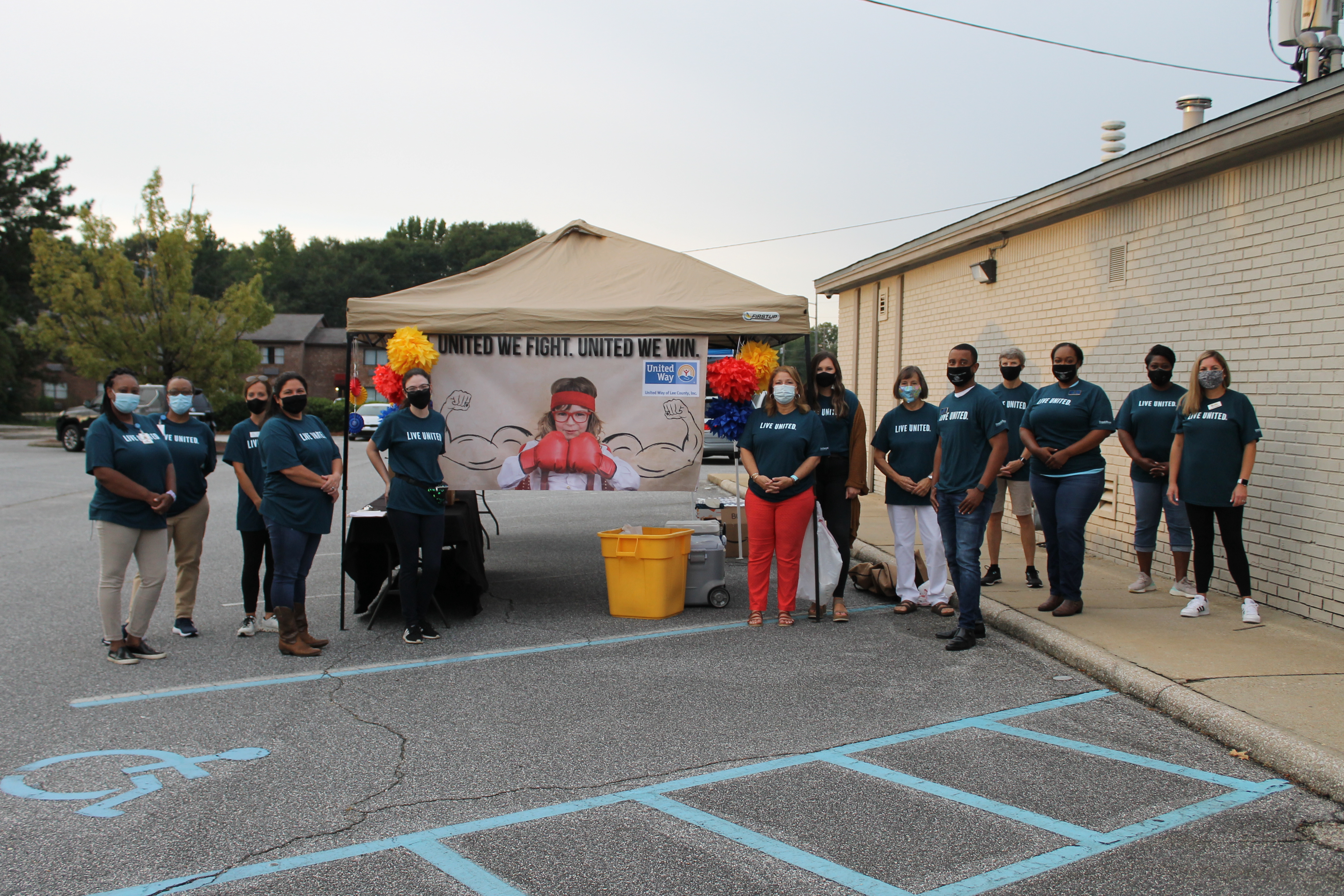 Aubie and United Way volunteers pose around the banner