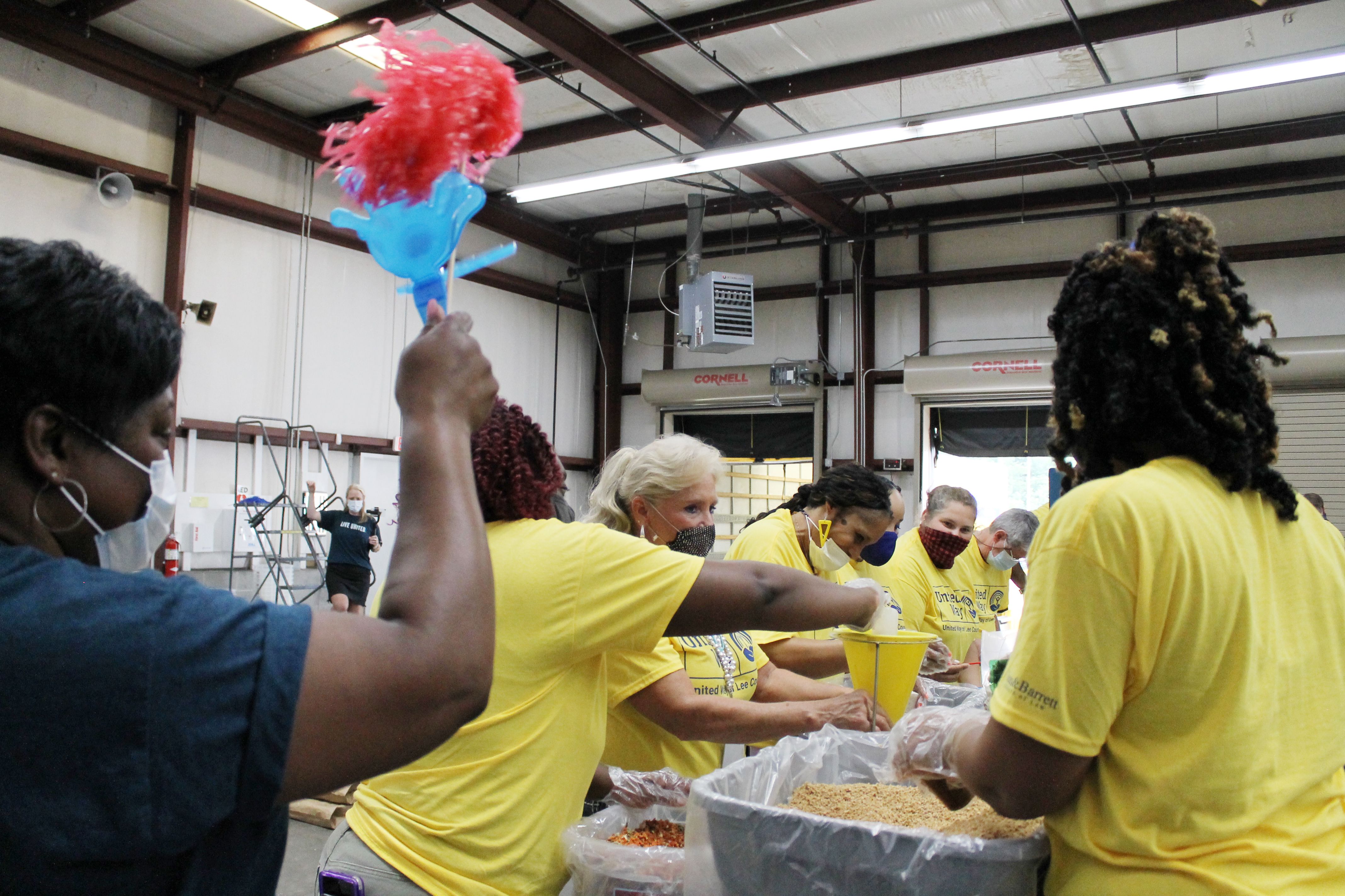 Volunteers packing food while the lead cheers them on