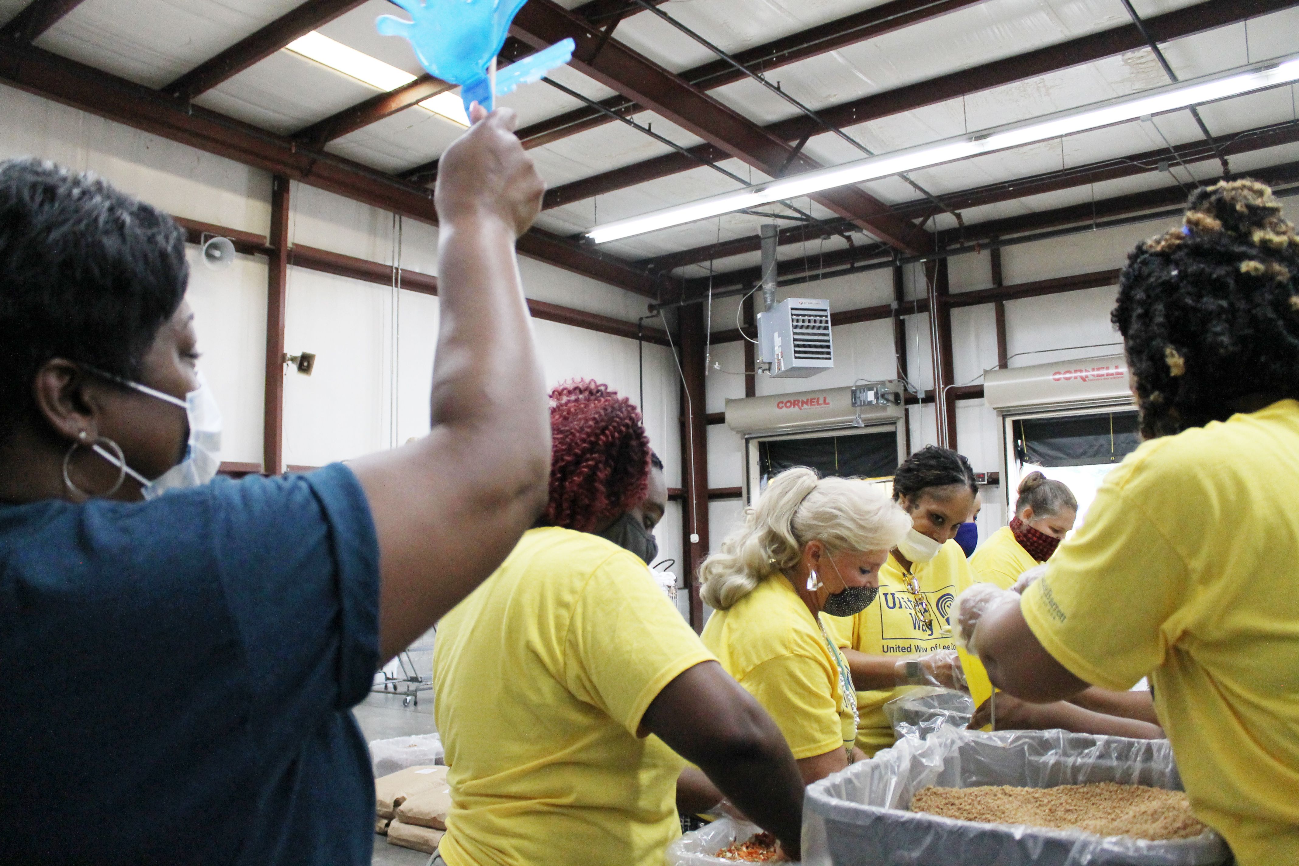 Volunteers packing food while the lead cheers them on